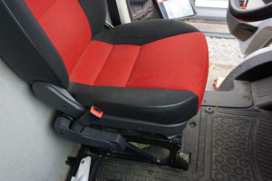 Vom Beifahrersitz aus fotografierter Fahrersitz im Fiat Ducato Typ 250 mit schwarz-rotem Bezug.